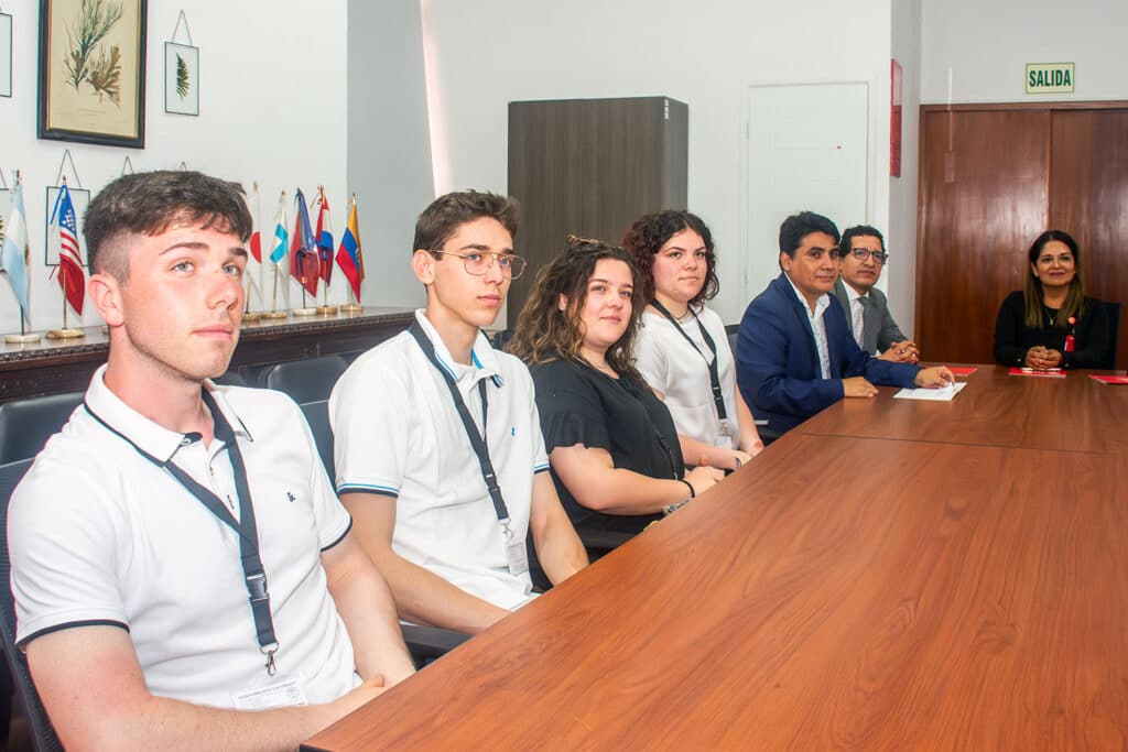 Cuatro estudiantes italianos de la Scuola Enologica G.B. Cerletti sentados en una mesa de reuniones en la UPSJB, escuchando atentamente.