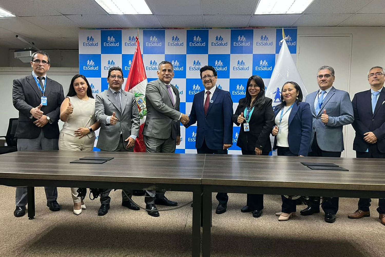 Toma amplia de grupo con autoridades y directivos de la UPSJB y EsSalud posando sonrientes y haciendo el gesto de pulgar arriba tras el apretón de manos que ratifica su convenio.