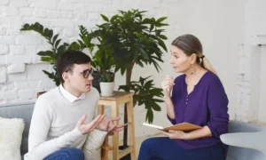 Psicólogo conversando con su paciente sobre enseñanza universitaria y su bienestar.