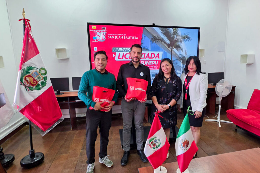 Internacionalización en Tecnología Médica: 5 claves que impulsan la excelencia UPSJB 3 Un grupo numeroso de personas, incluyendo a la Mg. Martha Reyes, directora de la EPTM, y al Mg. Ricardo Salas, posan juntas en una sala de reuniones. En primer plano, las banderas de Perú y México sobre una mesa. Al fondo, una pantalla con el logo de la UPSJB y una bandera peruana de pie.