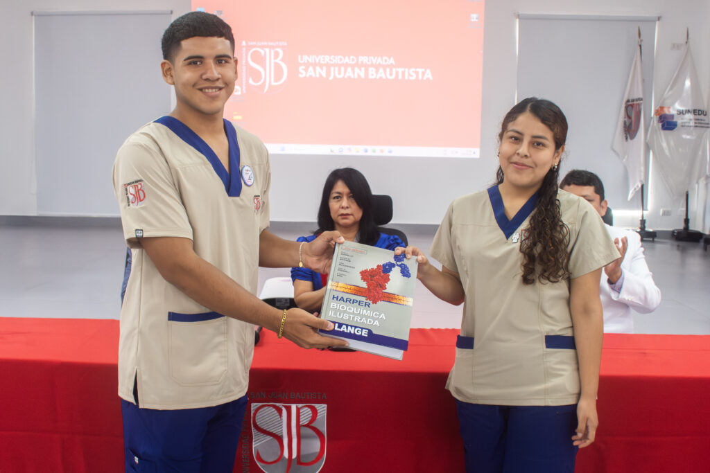 Estudiante de ciclos superiores entrega libro de Bioquímica a ingresante de Tecnología Médica UPSJB.