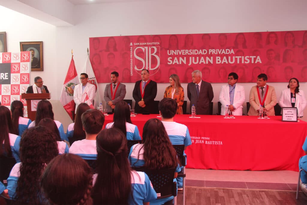 Vista del estrado principal de la ceremonia de batas de la UPSJB en Ica, con las autoridades académicas y el presidente fundador, Dr. José Luis Elías Ávalos, sentados frente al público.