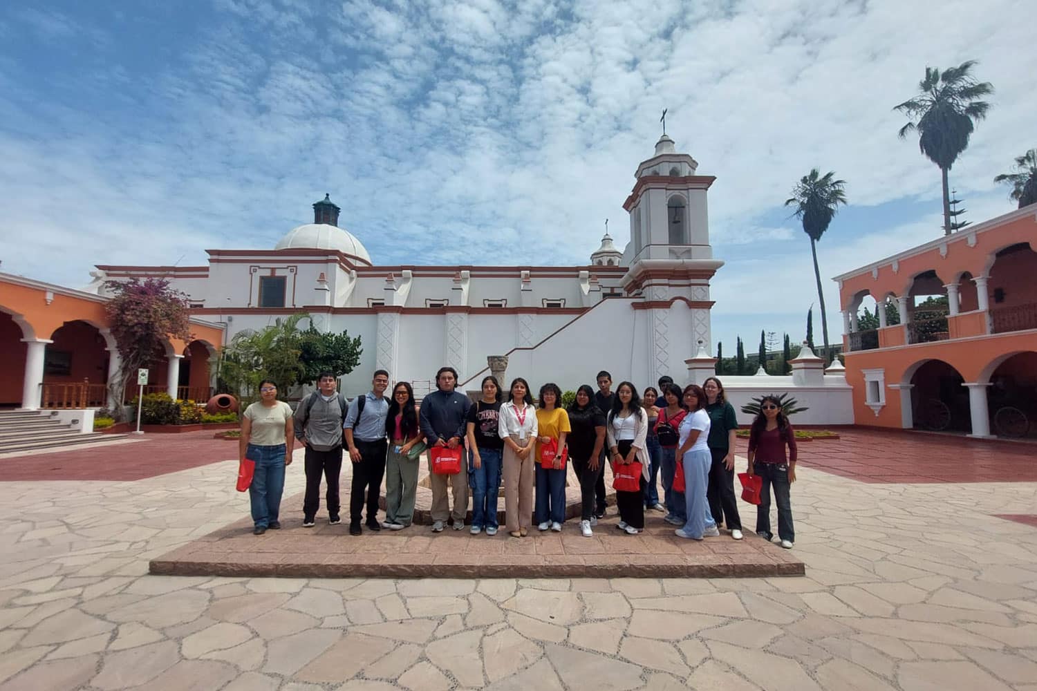 studiantes de la UPSJB posan frente a la capilla y la arquitectura colonial de la histórica sede de la universidad en Chorrillos.