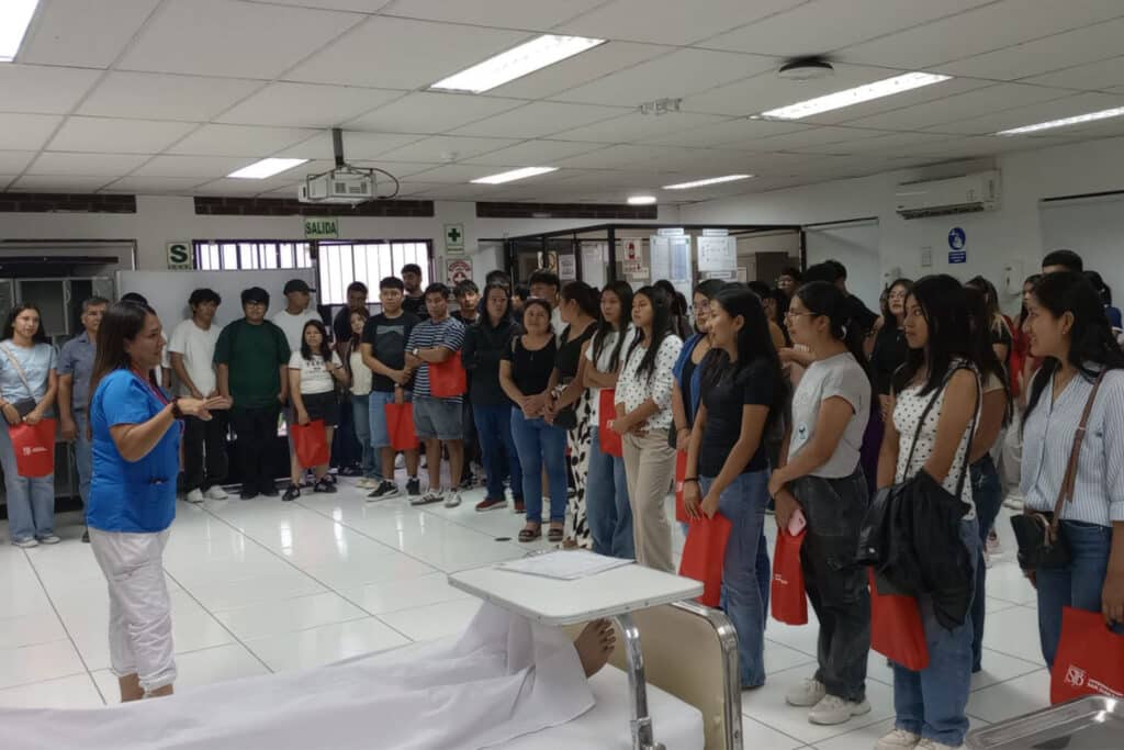 Una docente de la Facultad de Ciencias de la Salud de la UPSJB realiza una demostración de atención clínica con un maniquí de simulación frente a estudiantes.