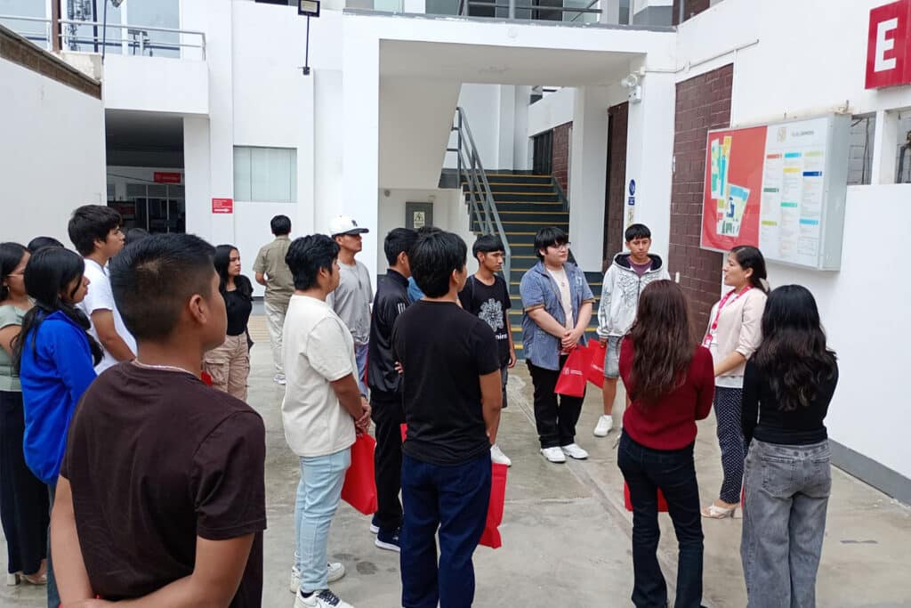 Una coordinadora académica explica el mapa del campus y la ubicación de aulas a un grupo de estudiantes en la filial Chincha de la UPSJB.