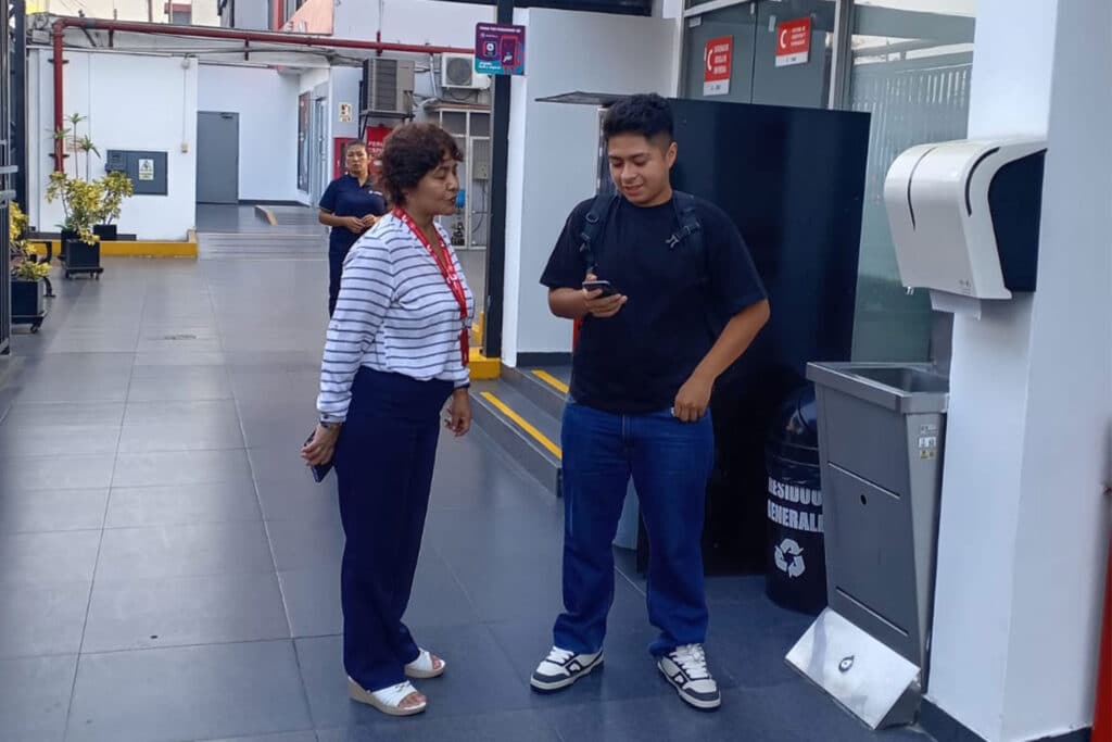 Colaboradora DABE brindando información a alumno con celular.