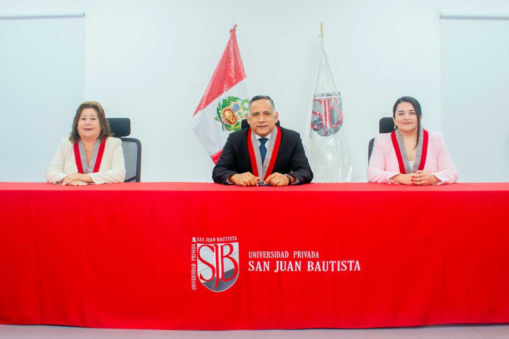 UPSJB realizó ceremonia de entrega de diplomas a nuevos maestros y especialistas 2 Mesa de honor de la UPSJB con la Dra. Sofía Romero Coz, el Rector encargado Dr. Alfredo Mendieta Leyva y la Mag. Marylin Cruzado Llanos sentados frente a un mantel rojo institucional.