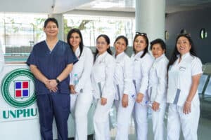 El Dr. John Paul Torres Navarro de la UPSJB junto a las residentes de la especialidad de Endodoncia posando frente al counter de recepción con el logo de la UNPHU durante la Pasantía internacional en Endodoncia.