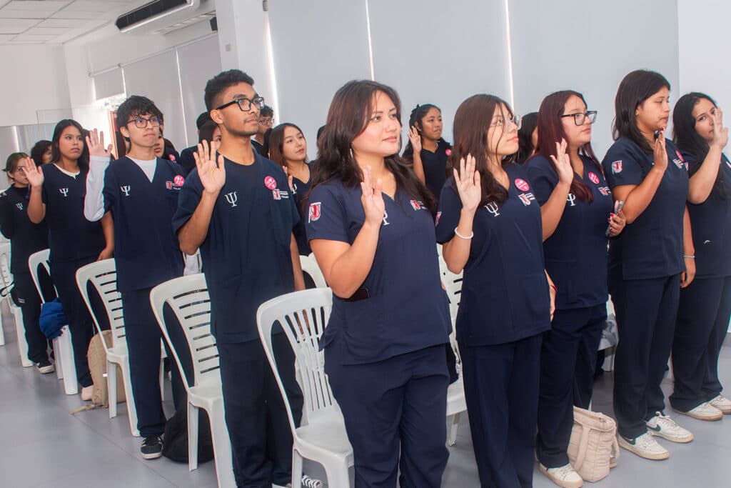 juramento-de-etica-estudiantes-psicologia-upsjb Estudiantes de la carrera de Psicología de la UPSJB de pie con la mano derecha alzada realizando el juramento ético profesional.