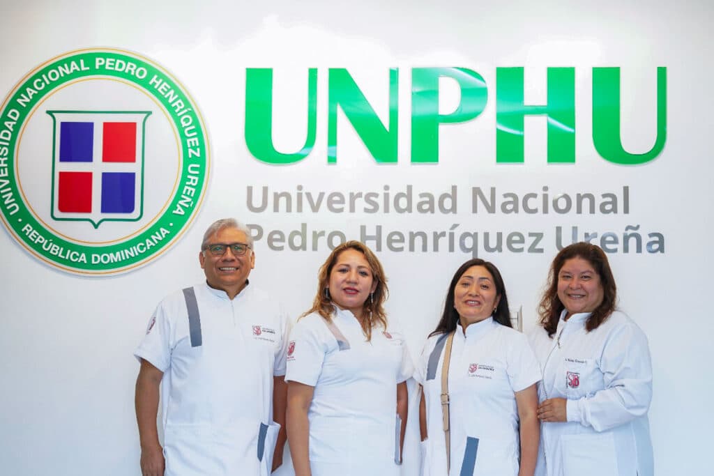 docentes-especialistas-endodoncia-upsjb-unphu Los docentes de la UPSJB, incluyendo a la Dra. María Luisa Ramos Inca Roca y la Dra. Milady Alvarado Villar, posando sonrientes bajo las letras corporativas verdes de la UNPHU.