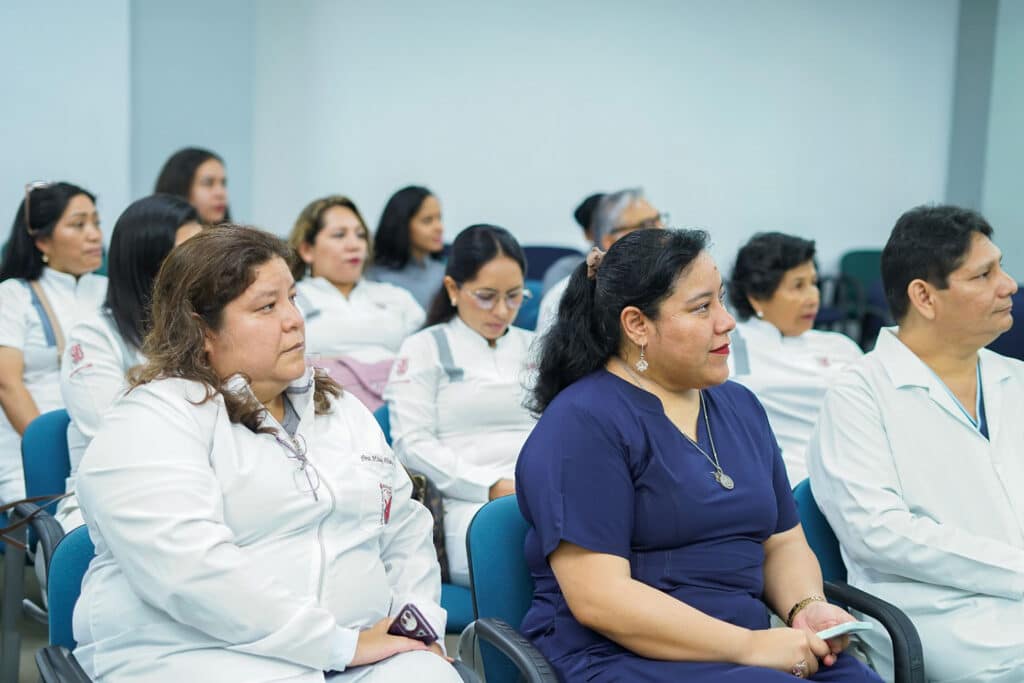 clases-teoricas-residentes-endodoncia-republica-dominicana Auditorio universitario con los profesionales de la UPSJB, como la Dra. Milady Alvarado Villar a la izquierda y el Dr. John Paul Torres Navarro a la derecha, sentados prestando atención.