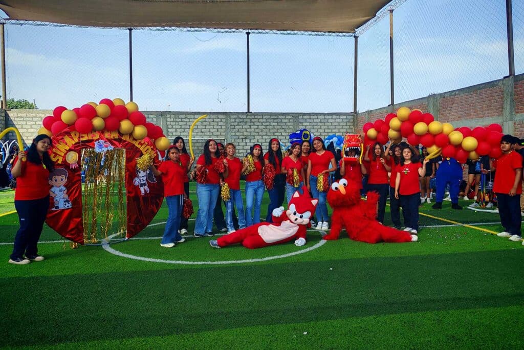 Grupo de estudiantes de Psicología de la UPSJB vestidos de rojo posando en una losa deportiva con globos y mascotas durante una jornada de integración.