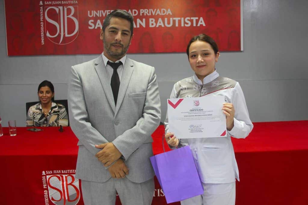 Estudiante de Estomatología de la UPSJB Ica recibe certificado durante la ceremonia La Primera Sonrisa junto a una autoridad académica.