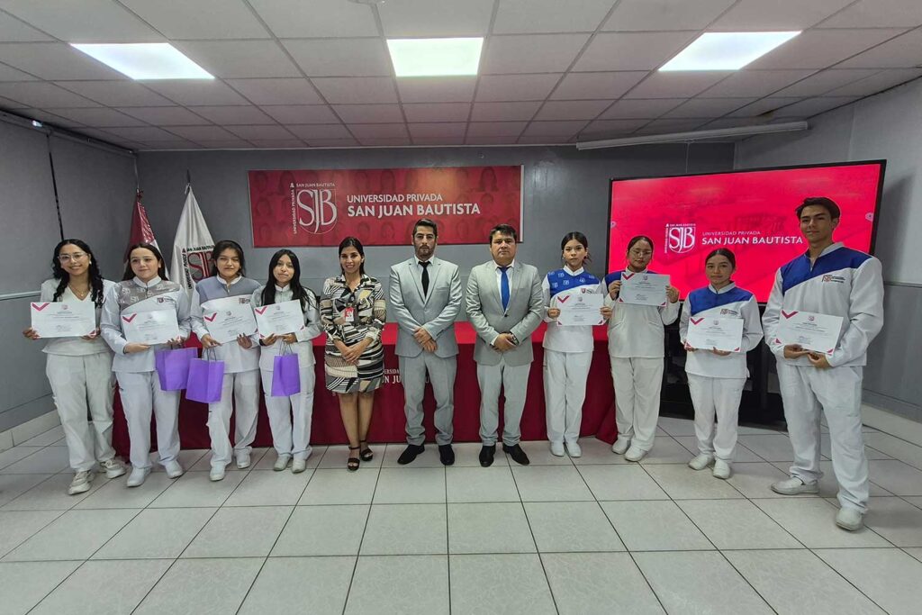 Estudiante de Estomatología de la UPSJB Ica recibe certificado durante la ceremonia La Primera Sonrisa junto a una autoridad académica.