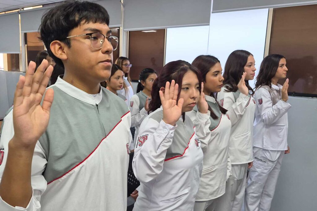 Estudiantes de Estomatología de la UPSJB Ica realizan juramentación levantando la mano durante la ceremonia La Primera Sonrisa.