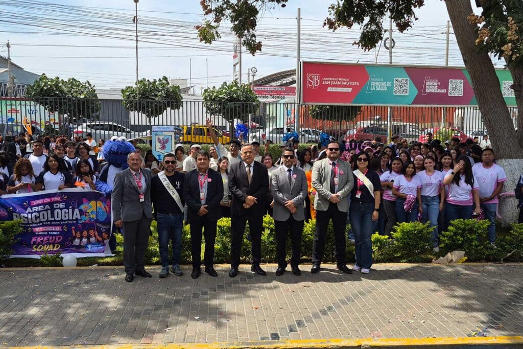 Autoridades universitarias y un gran grupo de estudiantes de Psicología de la UPSJB posando frente al ingreso de la sede institucional con banderolas informativas.