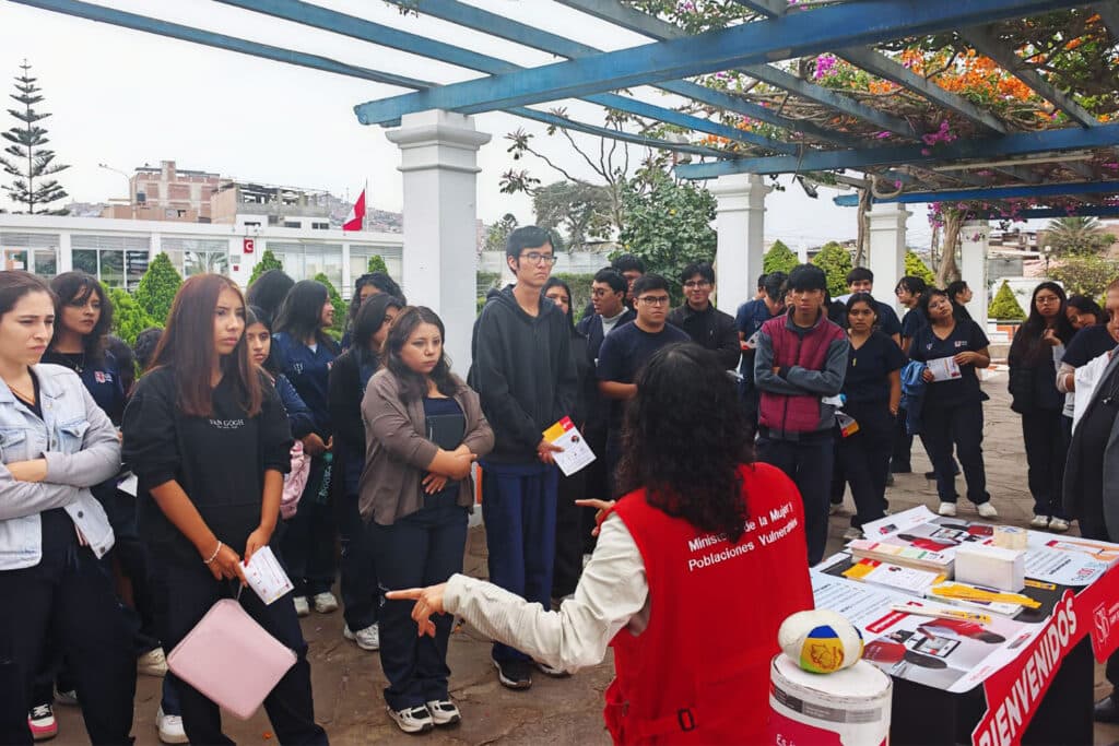 Grupo de estudiantes escucha atentamente la exposición de una especialista durante una jornada informativa sobre prevención de violencia y hostigamiento sexual en la universidad.