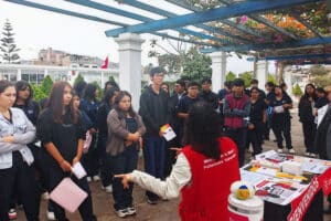 Grupo de estudiantes escucha atentamente la exposición de una especialista durante una jornada informativa sobre prevención de violencia y hostigamiento sexual en la universidad.