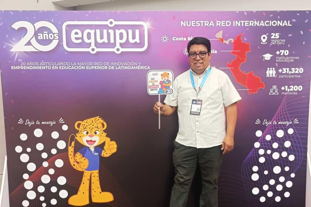dr-john-morillo-flores-reconocimiento-red-equipu-upsjb El Dr. John Morillo Flores de la UPSJB posando sonriente en el estrado mientras sostiene el galvano de reconocimiento institucional otorgado por la Red Equipu de la PUCP.