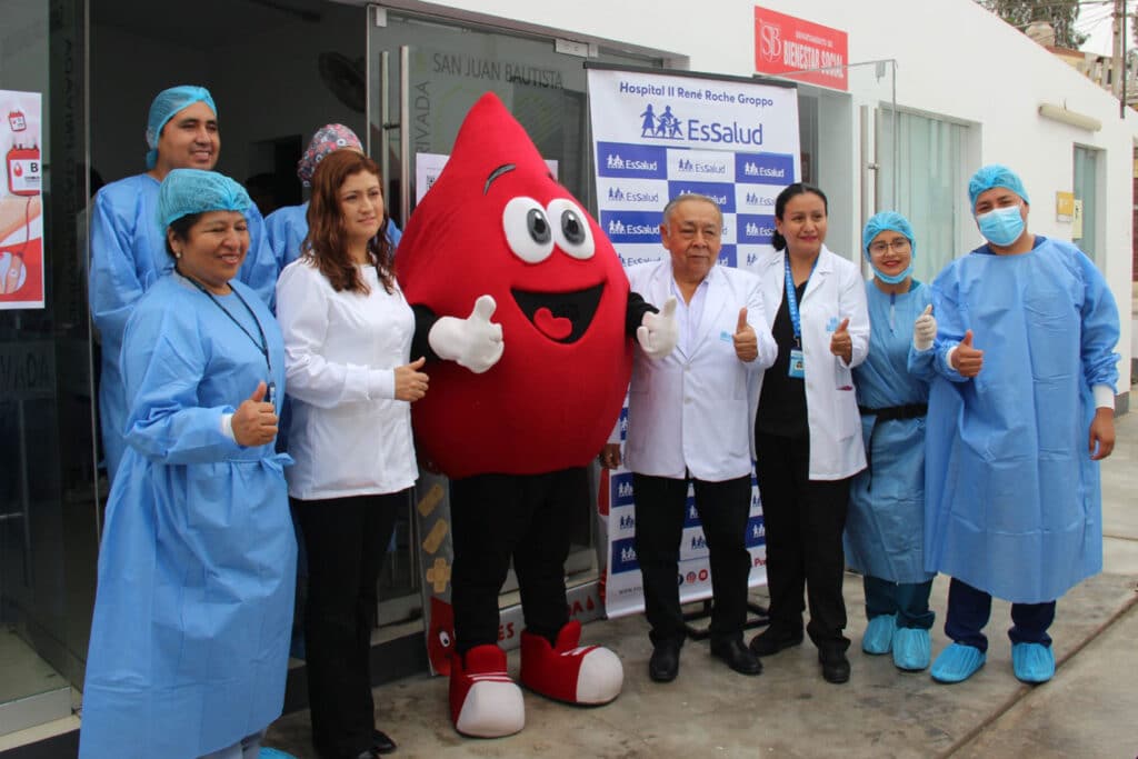 Grupo de autoridades universitarias y profesionales de salud posan junto a la mascota de una campaña de donación de sangre en las instalaciones de la UPSJB Filial Chincha.