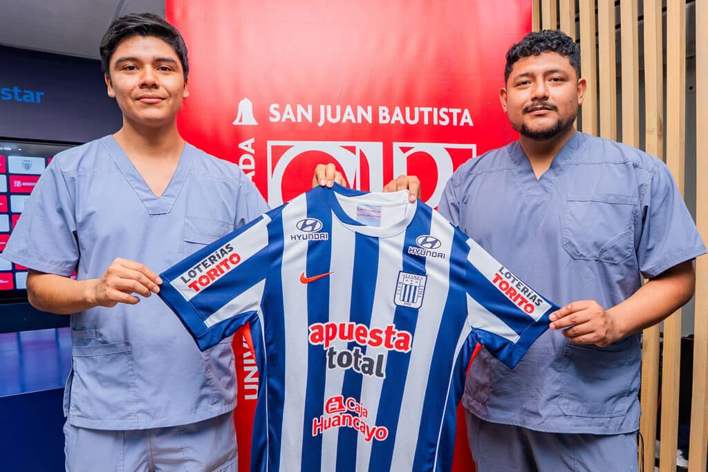 Convenio UPSJB y Alianza Lima: Colaboración estratégica por la salud y el deporte peruano 3 Junior Mendoza y Roy Herrera, estudiantes de la Escuela Profesional de Tecnología Médica, especialidad de Terapia Física y Rehabilitación de la UPSJB, muestran la camiseta oficial del Club Alianza Lima durante la firma del convenio institucional.