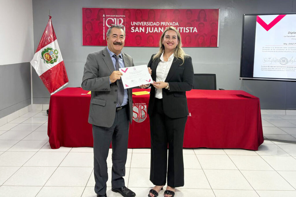 La decana de la Facultad de Derecho y Ciencias Empresariales entrega un diploma de reconocimiento a un docente durante la ceremonia por el Día del Docente Universitario en la UPSJB.