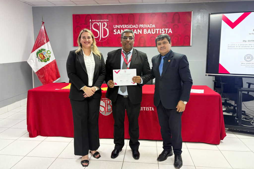 La decana de la Facultad de Derecho y Ciencias Empresariales y autoridades académicas acompañan a un docente durante la entrega de su diploma de reconocimiento a docentes universitarios en la Universidad Privada San Juan Bautista.