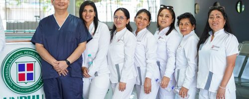 El Dr. John Paul Torres Navarro de la UPSJB junto a las residentes de la especialidad de Endodoncia posando frente al counter de recepción con el logo de la UNPHU durante la Pasantía internacional en Endodoncia.