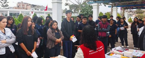 Grupo de estudiantes escucha atentamente la exposición de una especialista durante una jornada informativa sobre prevención de violencia y hostigamiento sexual en la universidad.