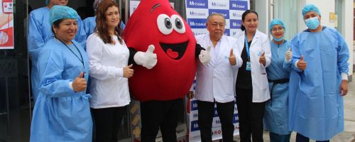 Grupo de autoridades universitarias y profesionales de salud posan junto a la mascota de una campaña de donación de sangre en las instalaciones de la UPSJB Filial Chincha.